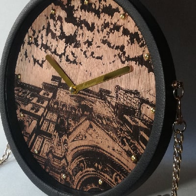 Particolare: Orologio artigianale con il Duomo di Firenze inciso a laser su legno. Cornice in ecopelle nera, dettagli dorati, e tracolla elegante. Stile unico e senza tempo.